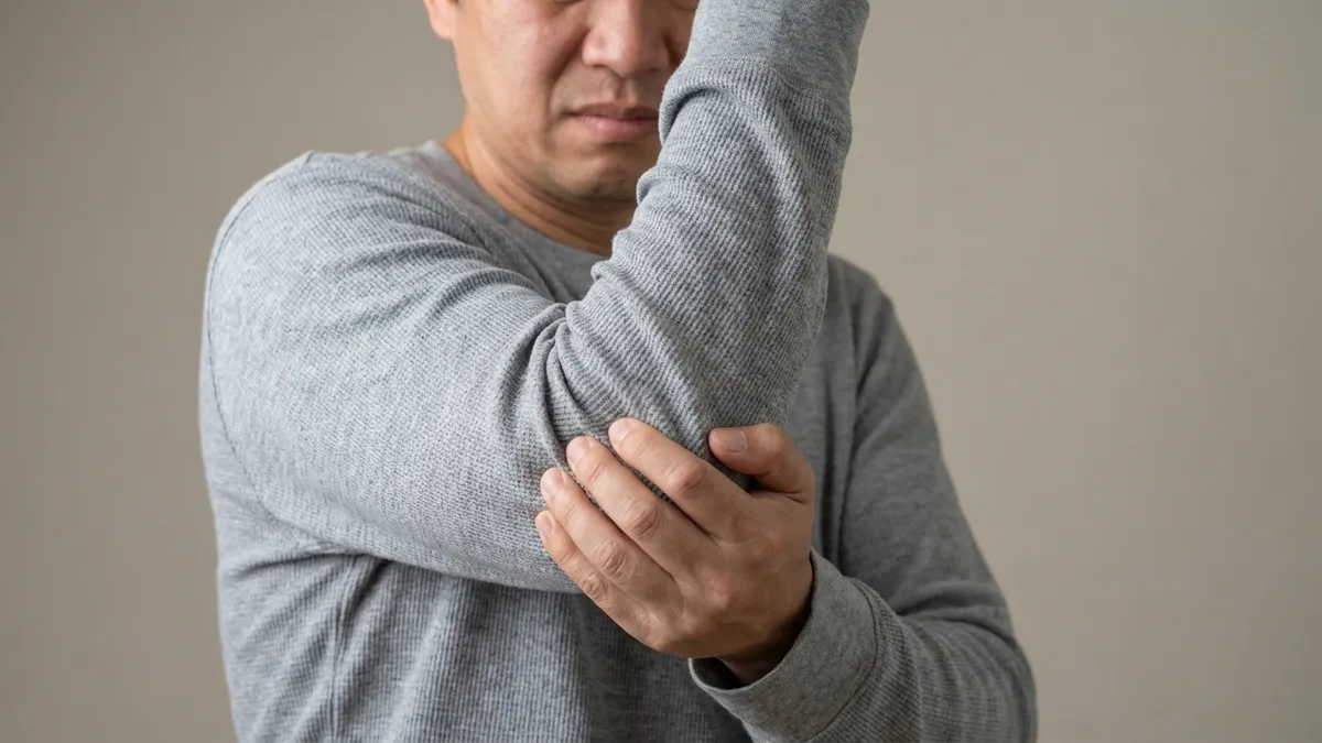 Person hält sich den schmerzenden Ellenbogen