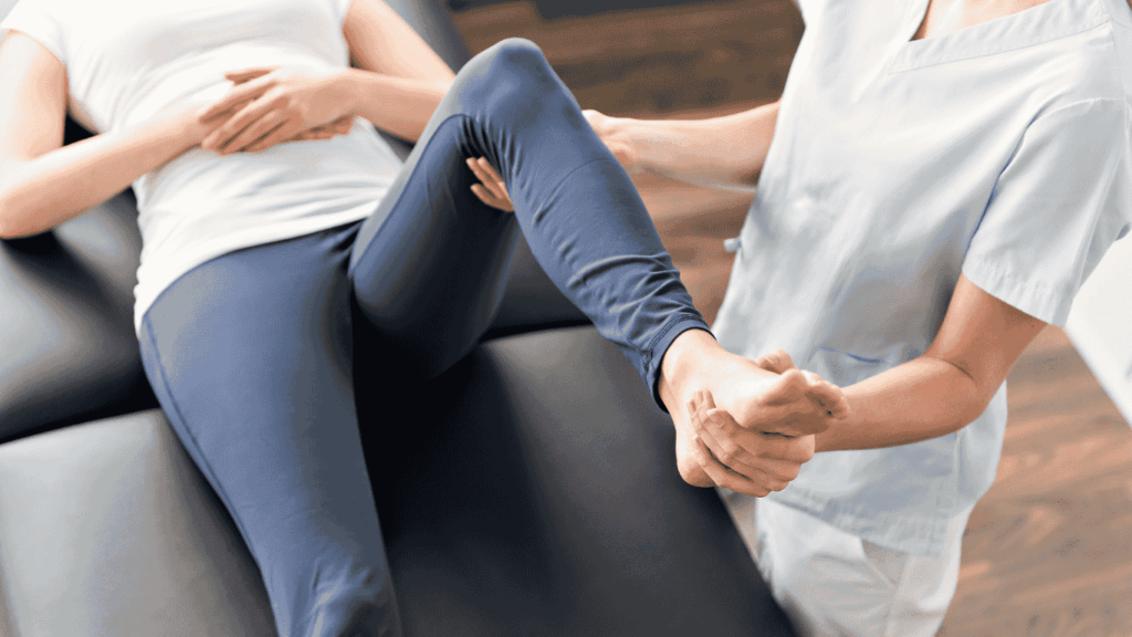 Ein Fachmann von Physio Lübeck hilft einer Person, die auf einer Liege liegt, indem er ihr Bein sanft beugt und stützt und ihr Knie und ihren Fuß während einer Rehabilitations- oder therapeutischen Übungseinheit führt.
